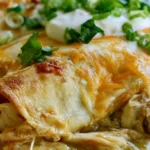 Hatch chili chicken enchiladas on a white plate with melted cheese and creamy green chile sauce