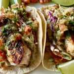 Fish tacos with crispy pan-seared fish, tangy cabbage slaw, and creamy sauce on warm tortillas