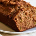 Apple cinnamon Zucchini bread sliced on a wooden board showing moist crumb and cinnamon swirl