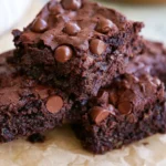 Double chocolate zucchini brownies cut into squares on a white plate showing fudgy texture