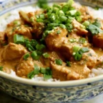 Coconut Chicken with golden crispy coating on a white plate with lime wedges and fresh herbs