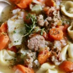 Autumn Tortellini Soup with Sausage in a rustic bowl topped with parmesan cheese and fresh herbs
