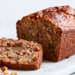 Cinnamon apple bread sliced on a wooden board showing moist crumb and cinnamon swirl