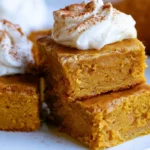Pumpkin bars with cream cheese frosting cut into squares on a white platter