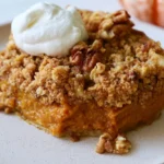 Pumpkin pie crisp with golden streusel topping served in white dish with whipped cream