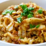 Dirty cabbage with ground beef and bacon served in a cast-iron skillet, garnished with green onions