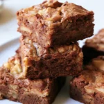 apple brownies on white plate showing golden brown bars with visible apple pieces and cinnamon