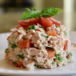 Tuna salad recipe served in a white bowl with celery and onion on a wooden table