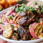 Sticky Apple Cider Chicken with Autumn Slaw plated on a white dish with caramelized glaze and colorful cabbage slaw