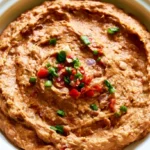 Refried beans served in a rustic bowl with a dollop of sour cream and fresh cilantro garnish