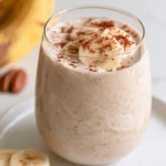 Protein shake recipe in a tall glass with a creamy texture and fresh berries on top