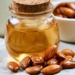 Almond extract in a small amber glass bottle with raw almonds scattered on a wooden surface