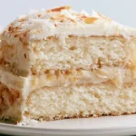 Vanilla cake recipe showing two golden layers with smooth buttercream frosting on a white cake stand