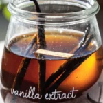 Homemade Vanilla extract in a glass bottle with split vanilla beans steeping in amber liquid