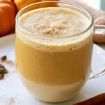 Homemade pumpkin creamer swirled into a white mug of hot coffee on a wooden table with fall spices