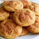 Pumpkin snickerdoodle cookies stacked on a white plate with cinnamon sugar coating