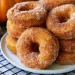 Pumpkin donuts with glaze arranged on a white plate with fall spices in the background