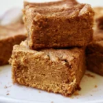 Pumpkin snickerdoodle brownies cut into squares with cinnamon sugar topping on a white plate