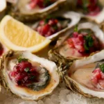 Mignonette recipe in a small glass bowl next to fresh oysters on the half shell on ice