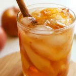 Korean Apple tea served warm in a clear glass mug garnished with apple slice and cinnamon stick