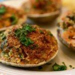 Stuffed clams with golden crispy breadcrumb topping served on a white platter with lemon wedges