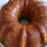 Pumpkin bundt cake dusted with powdered sugar on a white serving plate