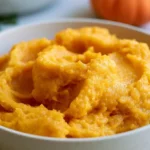 Pumpkin puree recipe in a white bowl with a spoon on a wooden table