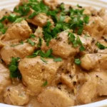 Chicken au poivre with creamy peppercorn sauce on a white plate with fresh parsley