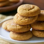 Pumpkin sugar cookies arranged on a white plate with cream cheese frosting and fall decorations