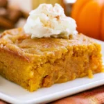 Pumpkin dump cake with golden topping served warm on a white plate with vanilla ice cream