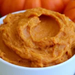 Pumpkin butter spread on toast with a jar of smooth spiced pumpkin butter in the background