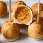 Pumpkin pie cake pops coated in white chocolate and drizzled with cinnamon on a serving platter