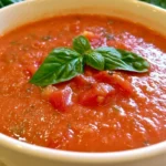 Tomato basil soup in a white bowl garnished with fresh basil and a drizzle of olive oil