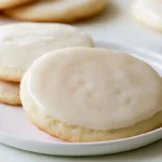 Sugar cookie icing in a white bowl with a whisk, showing a smooth glossy glaze