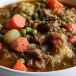 Beef vegetable soup in a white bowl with visible chunks of beef, carrots, green beans, and potatoes in rich broth