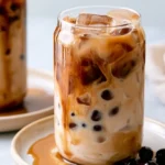 Brown sugar milk tea in a tall glass with tiger stripes and ice, garnished with a straw