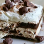 Dirt cake in a 9x13 pan with layers of crushed Oreos, pudding, and cream cheese topped with cookie crumbs and gummy worms