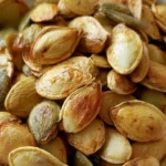 Pumpkin seeds recipe showing crispy golden roasted seeds in a white bowl on a rustic wooden table