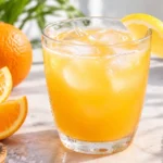 Cortisol drink recipe in a clear glass with orange juice and coconut water, garnished with ice and served on a light countertop