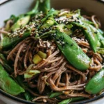 Soba noodles in a white bowl with dashi broth, shiitake mushrooms, bok choy, soft boiled egg halves, and green onions on top