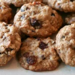 Oatmeal raisin cookies stacked on a white plate with visible oats and raisins