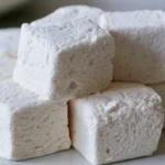 Apple marshmallow recipe dusted with cornstarch on a white plate with fresh apple slices