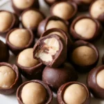 Buckeyes on a white plate with a circle of peanut butter showing on top of each chocolate coated candy