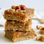 Date caramel in a glass jar with a spoon, showing thick, smooth caramel drizzled over the edge