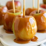 Kraft caramel apples on wooden sticks arranged on parchment paper with glossy caramel coating