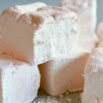 Homemade marshmallow recipe cut into squares and dusted with powdered sugar on a white plate