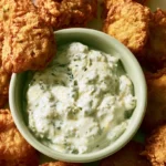 Tartar sauce in a white bowl with dill pickles and fresh dill visible on top
